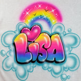 Lisa in shaded yellow, pink, purple and blue bubble letters beneath a rainbow and pink heart, surrounded by turquoise cloud-like outlines on white fabric.