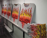 Five gray Denessa flame-name shirts displayed on studio easels, with a stack of matching shirts at the front right, showing hand-airbrushed group orders.