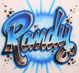 Original hand-airbrushed Randy name in chrome-effect block script, with blue highlights, dark reflective shading, swirls and starbursts on white fabric.