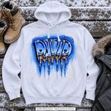 White hoodie styling mockup with David in blue icy block letters and long icicle drips, arranged on a snowy bench beside winter boots and a coat.