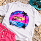 Chris loves Brittany sunset wave artwork centered on a white shirt, styled on a beach boardwalk with pink shorts, teal visor and sunglasses; digital mockup.