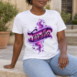 Seated-model styling mockup of a white T-shirt with original Juanita black script, pink and purple swirls and white star highlights, paired with light blue jeans.
