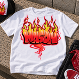 Styled mockup of a white Mason flame-name airbrush shirt on concrete, with a partly cropped hat, black jeans and red accessories. Shirt sold separately.